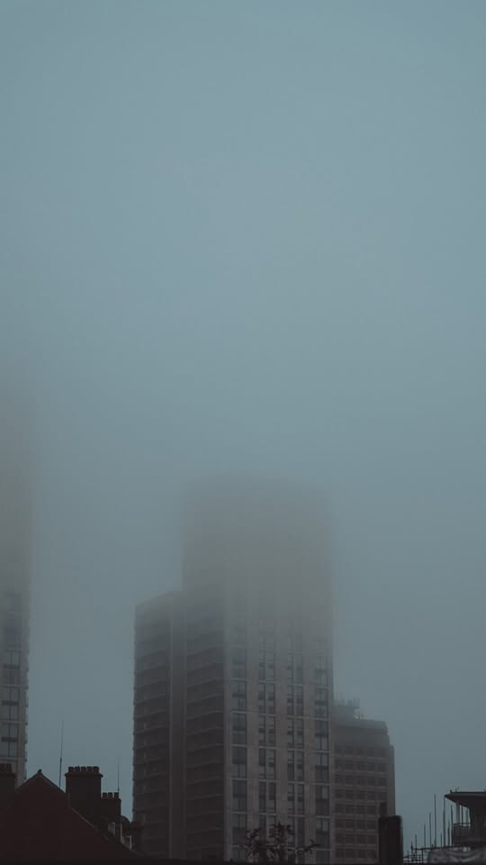 High-rise city buildings partially obscured by thick grey fog