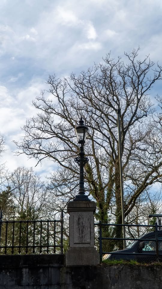 Ornate black Victorian-style lamppost on a stone pedestal