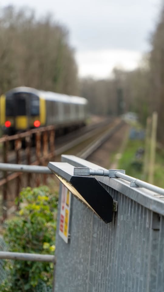 Grey corrugated metal bridge structure with a blurred passenger train in background